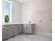 Well-lit laundry room with a sink, neutral gray cabinets, marble flooring, and wire racks at 115 Thome, Alpharetta, GA 30022