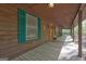 Exterior view showcasing a covered porch with natural wood flooring, green shutters, and an orange door at 3452 Monica Sw Ln, Conyers, GA 30094