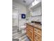 Bathroom with white-tile walls, wood cabinets, granite counters, updated fixtures, and a shower-tub combo at 1026 Ponderosa Park Dr, Forest Park, GA 30297