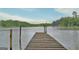 Wooden dock extends into a tranquil lake, surrounded by verdant trees, offering serene waterfront enjoyment at 270 E James Cir, Hampton, GA 30228