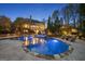 Stunning pool with a waterfall feature, surrounded by lush landscaping and an illuminated two-story home at 113 Regents Sq, Peachtree City, GA 30269