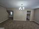Open-concept living space with neutral walls, a modern chandelier, and views of the staircase at 1110 Saint Phillips Ct, Locust Grove, GA 30248