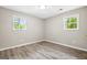Bright bedroom featuring wood-look flooring and natural light from two windows at 5724 Amalfi Way, Douglasville, GA 30135