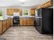 Well-lit kitchen with wood cabinets, black appliances and laminate flooring at 5724 Amalfi Way, Douglasville, GA 30135