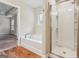 Bright bathroom featuring a soaking tub, glass-enclosed shower, and wood-look flooring at 12323 Styron Dr, Hampton, GA 30228