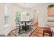 A cozy dining area with a round table, four chairs, and natural light from the adjacent windows at 12323 Styron Dr, Hampton, GA 30228