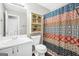 A compact bathroom that includes a toilet, single sink vanity, decorative shower curtain, and a cabinet at 130 Belmont Trl, Covington, GA 30016