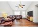 Bright living room features a ceiling fan, wood-look floors, and comfortable leather furniture at 130 Belmont Trl, Covington, GA 30016