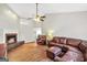 Cozy living room with a stone fireplace, ceiling fan, and leather furniture at 130 Belmont Trl, Covington, GA 30016