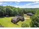 An aerial view showcasing a brick home on a sprawling lot with mature trees and a swimming pool in the distance at 3950 Chattahoochee Rd, Cumming, GA 30041