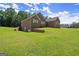 Rear exterior featuring a brick home with a manicured lawn and mature trees at 3950 Chattahoochee Rd, Cumming, GA 30041