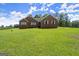 Charming brick home with lush green lawn, complemented by well-maintained landscaping and a serene countryside backdrop at 3950 Chattahoochee Rd, Cumming, GA 30041
