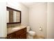 A bathroom with a wooden vanity with granite top, toilet, and framed mirror at 1017 Ridgefield Dr, Peachtree City, GA 30269
