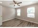 A cozy bedroom featuring wood-look floors, a ceiling fan, and two windows with bright natural light at 1017 Ridgefield Dr, Peachtree City, GA 30269