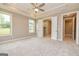 Carpeted main bedroom featuring a ceiling fan, ensuite bathroom and access to a walk-in closet at 209 Cottonwood Cir, Peachtree City, GA 30269
