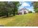 Stunning view of the home's rear exterior with a spacious backyard, wooden deck, and verdant landscaping at 44 Willow Leaf Way, Sharpsburg, GA 30277