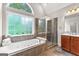 Bright bathroom featuring a soaking tub, glass-enclosed shower, and a large window at 44 Willow Leaf Way, Sharpsburg, GA 30277