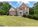 Lovely two-story brick home featuring manicured lawn, lush landscaping, and charming architectural details at 44 Willow Leaf Way, Sharpsburg, GA 30277