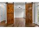 View of a living area with hardwood floors and rustic wood sliding doors at 44 Willow Leaf Way, Sharpsburg, GA 30277