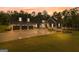 Beautiful exterior of home with large driveway and three-car garage, with a colorful sunset in the background at 180 Lapis Lake Pt, Fayetteville, GA 30215