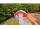 Aerial view of a vibrant red barn featuring a metal silo and a gravel driveway, surrounded by trees at 75 Barber Rd, Carrollton, GA 30116