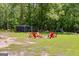Outdoor fire pit surrounded by six Adirondack chairs on a sprawling green lawn near mature trees at 75 Barber Rd, Carrollton, GA 30116