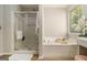 Bright bathroom featuring a shower, soaking tub, wood-look floors, and a vanity with white cabinets at 1444 Gates Se Cir, Atlanta, GA 30316