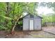 Exterior view of the shed with covered porch and white door, nestled in the trees at 1590 Colonial South Sw Dr, Conyers, GA 30094
