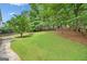 Expansive backyard with lush green grass, mature trees, and a stone walkway, perfect for outdoor activities at 2010 Pearwood Path, Roswell, GA 30076