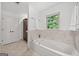 A clean, white bathroom with a tub under the window and marbled tile at 2010 Pearwood Path, Roswell, GA 30076