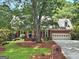 Traditional red brick home featuring a manicured lawn and a two-car garage nestled among mature trees at 2010 Pearwood Path, Roswell, GA 30076