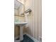 Elegant half-bath with pedestal sink, decorative mirror, and striped wallpaper creating a charming and inviting space at 40 Costleys Bridge Dr, Oxford, GA 30054