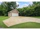 Detached garage with a paved driveway, complemented by lush greenery and mature trees at 15 Livingston Way, Covington, GA 30016
