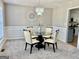 Elegant dining room with a round glass table, four chairs, decorative chandelier, and white wainscoting at 355 Woodbyne Dr, Fayetteville, GA 30214