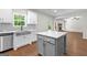 Bright eat-in kitchen features white cabinetry, stainless appliances, gray backsplash, island and hardwood floors at 74 Riverwood Trl, Grantville, GA 30220
