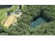 Aerial view of a home, paddock, and pond surrounded by lush trees at 135 Brookshire Dr, Fayetteville, GA 30215