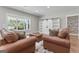 Comfortable living room with neutral paint, bright windows, and plush leather seating at 135 Brookshire Dr, Fayetteville, GA 30215