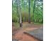 View of a backyard featuring bamboo, trees, an old barrel, and a concrete patio area at 106 Garden Trl, Stockbridge, GA 30281