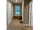 Carpeted hallway features a storage bench, multiple doorways and a window, creating an inviting thoroughfare at 175 Bridgemill Dr, Covington, GA 30014