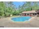 Large backyard pool surrounded by lush trees and an ample concrete patio at 9706 Holly Hill Way, Jonesboro, GA 30238