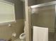 Bathroom featuring neutral-toned square tiles, a toilet, a shower with a glass door, and a bright window at 7111 Indian Creek Sw Cir, Covington, GA 30014