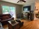 Cozy living room featuring wood flooring, a ceiling fan, a sliding glass door, and a fireplace with a TV above at 7111 Indian Creek Sw Cir, Covington, GA 30014