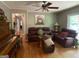 Living room featuring hardwood floors, comfortable seating, a ceiling fan, and a view into the hallway at 7111 Indian Creek Sw Cir, Covington, GA 30014