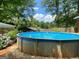 Backyard above ground pool surrounded by a beautifully landscaped yard and mature trees at 7111 Indian Creek Sw Cir, Covington, GA 30014
