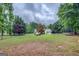 Large backyard featuring a spacious lawn with mature trees, trampoline and playset at 160 Laurel Ln, Social Circle, GA 30025