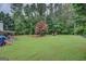 Large backyard featuring a spacious lawn with mature trees and playground area at 160 Laurel Ln, Social Circle, GA 30025