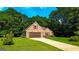 Inviting brick home with attached garage, complemented by lush greenery, and a well-kept lawn at 6830 Peeksville Rd, Mcdonough, GA 30252