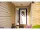 Inviting front door with decorative wreath, sidelight window, and neutral siding, set in a cozy, landscaped entrance at 6830 Peeksville Rd, Mcdonough, GA 30252