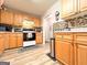 View of kitchen featuring wood cabinets, tiled backsplash, and modern appliances with wood-look flooring at 6830 Peeksville Rd, Mcdonough, GA 30252