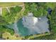 Aerial view of a beautiful lake with a dock and a luxurious property with a pool surrounded by greenery at 3612 Bill Gardner Pkwy, Locust Grove, GA 30248